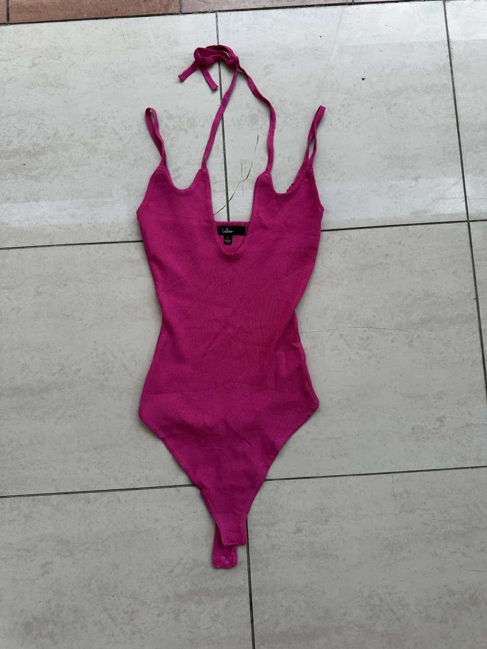 Body de modal color fucsia con tiras finas y escote pronunciado. Posee tiras para atar en la nuca.