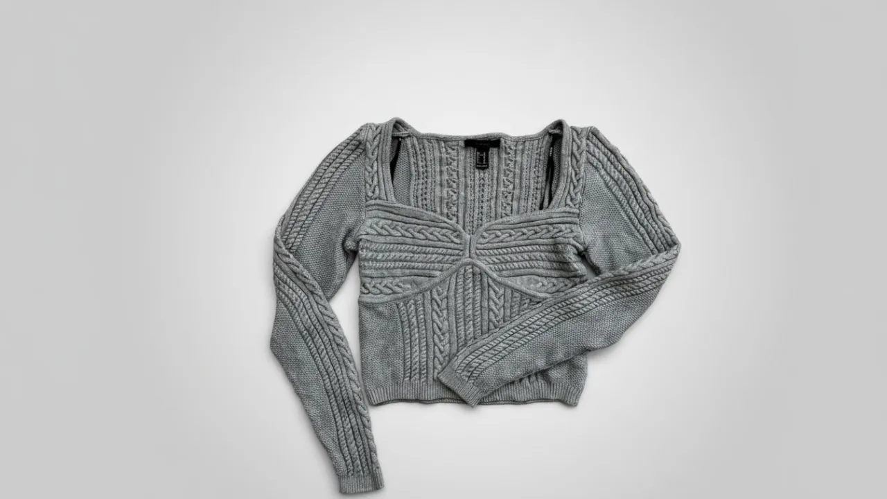 Sweater gris con trenzas y detalles tejidos en mangas y frente. Escote cuadrado.