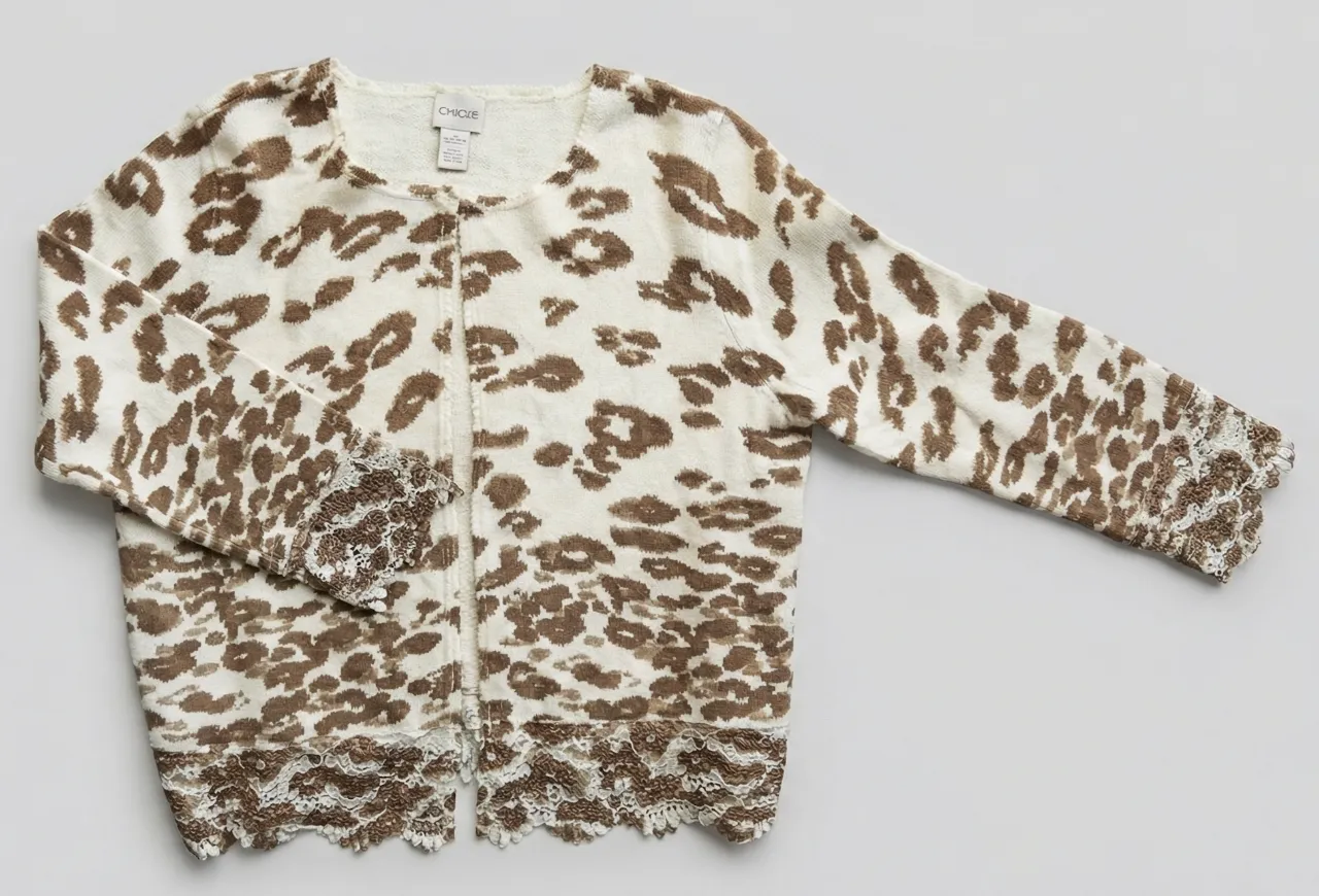 Cardigan de tejido con estampa animal print de leopardo en tonos blanco y marrón. Posee detalles de encaje en puños y ruedo inferior. Se abrocha al frente con botones.