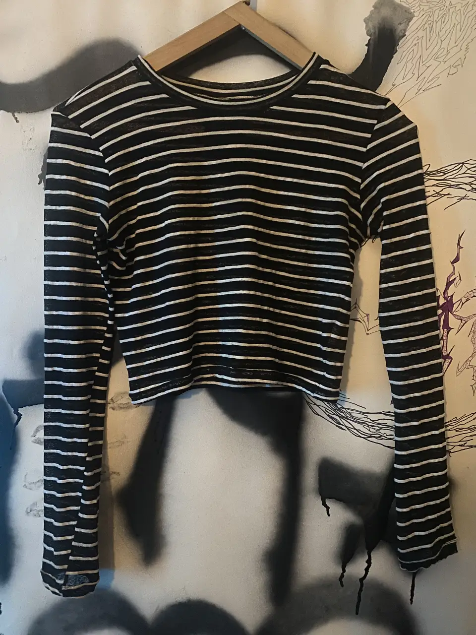 Remera Complot manga larga a rayas horizontales en blanco y negro, de corte crop. Ideal para un look casual y moderno.