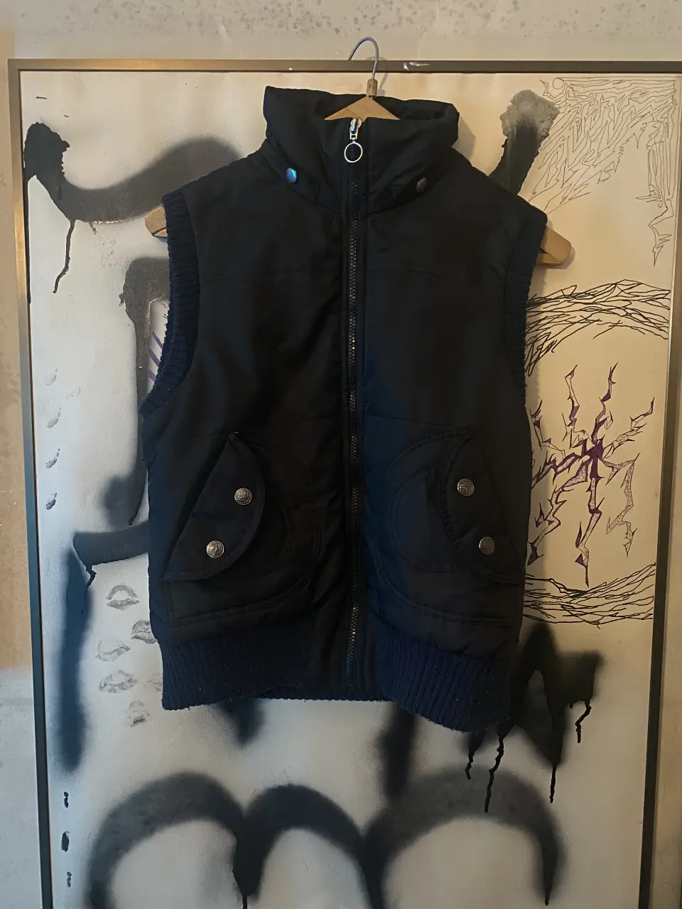 Chaleco negro acolchado con cierre y bolsillos delanteros. Ideal para el invierno, abrigo y estilo en una sola prenda.