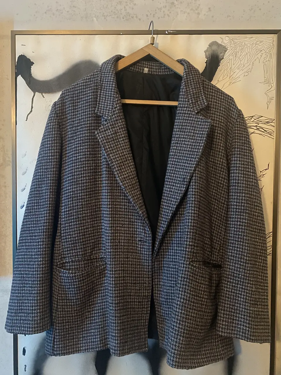 Blazer con diseño de espiga en tonos grises y negros. Corte clásico con solapas y bolsillos delanteros. Ideal para un look elegante y versátil.