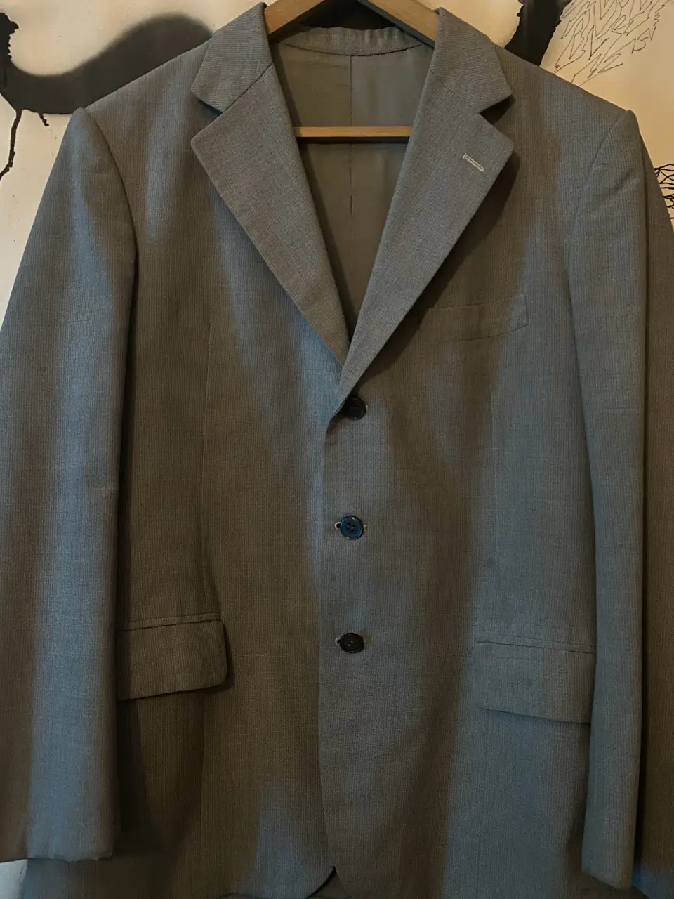 Blazer gris de hombre, ideal para un look formal o de trabajo. Corte clásico con tres botones y bolsillos.