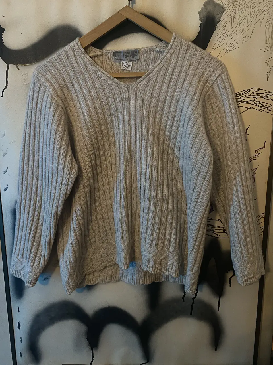 Sweater de punto en V, color crudo, con detalle de diseño en el bajo. Ideal para un look casual y abrigado.