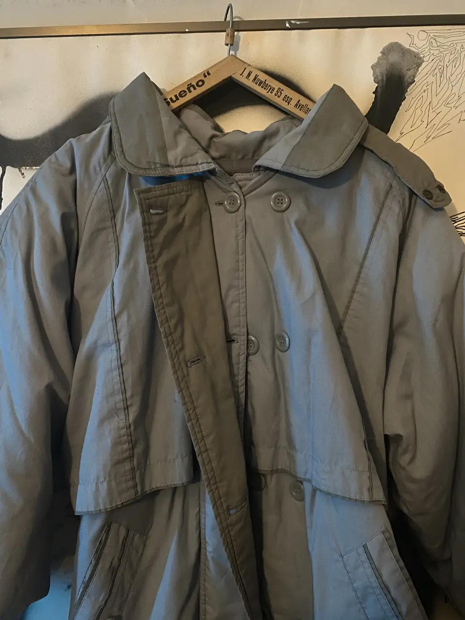 Trench gris con cuello solapa y cinturón. Ideal para el invierno, con un estilo vintage. Es como andar con una frazada encima, muy abrigado.