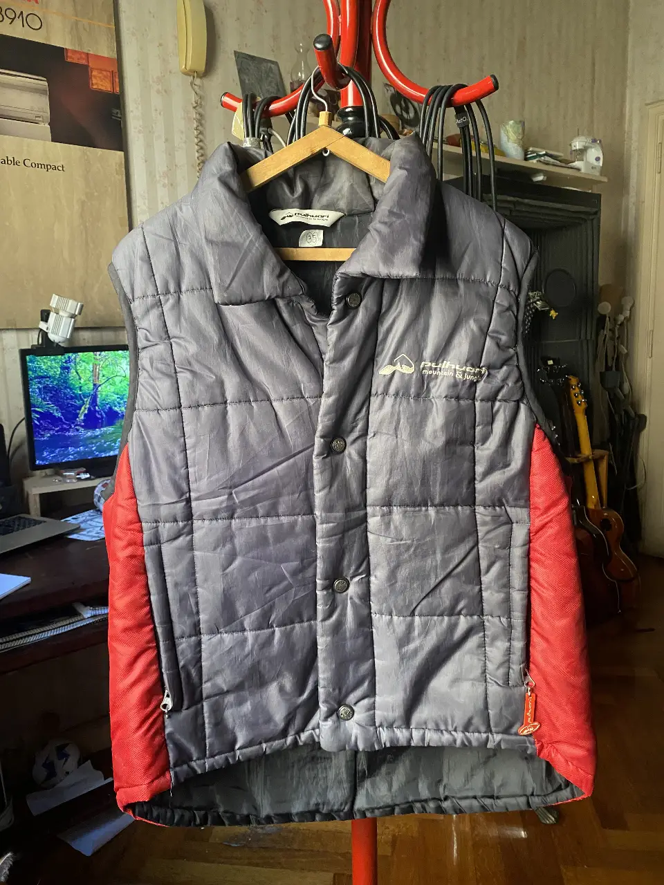 Chaleco Pullin Mountain & Jungle gris con detalles rojos. Ideal para actividades al aire libre o uso diario. Diseño acolchado y cierre con botones.