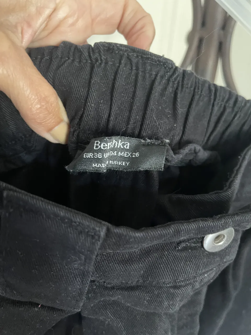 Pantalón cargo negro con cintura elastizada y bolsillos traseros. Detalle de botón en la cintura.