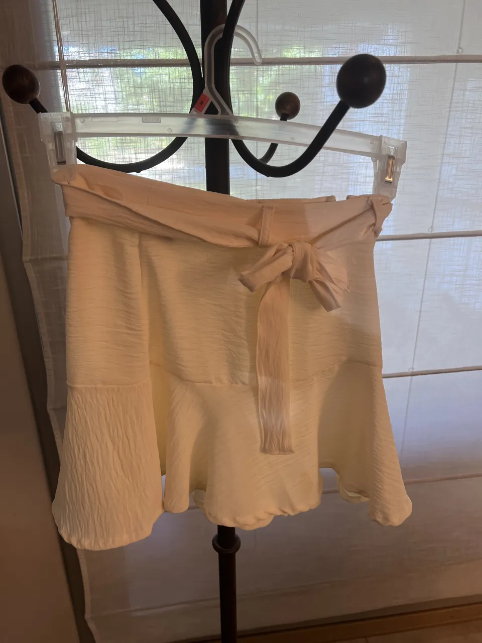 Pollera corta color crudo con cinturón de tela anudado en la cintura. Posee volados en la parte inferior. cintura 34 cm. largo 39. cadera 44 cm