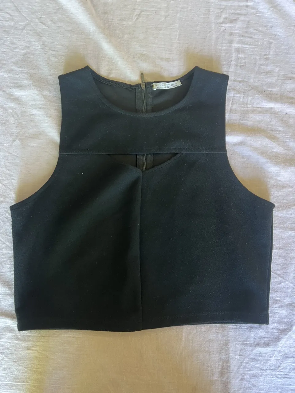 Top negro con cierre en la espalda y detalle de corte en el frente.