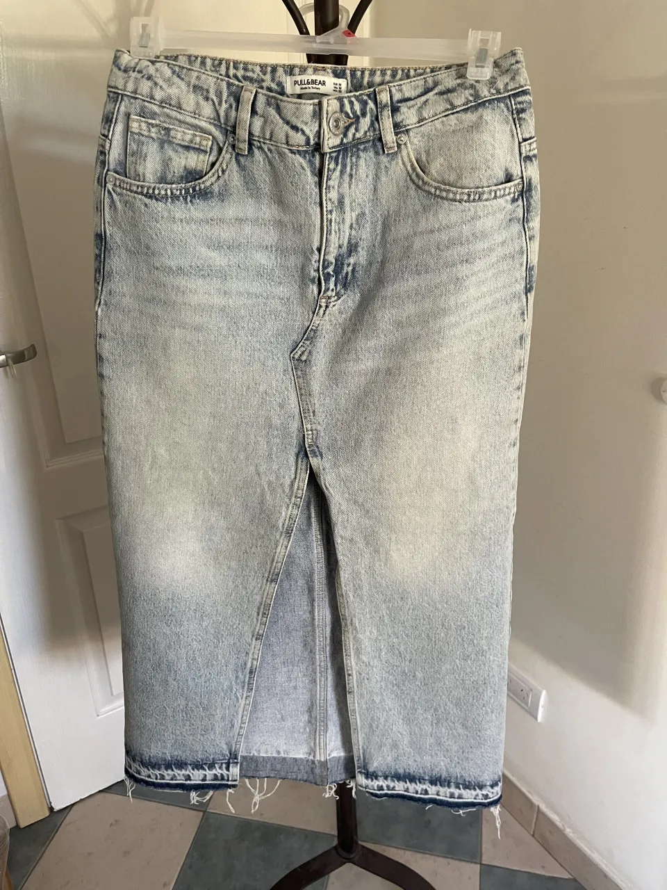 Pollera de jean larga, tiro alto, con tajos en el frente y terminación deshilachada en el ruedo. Lavado celeste desgastado. cintura 40cm