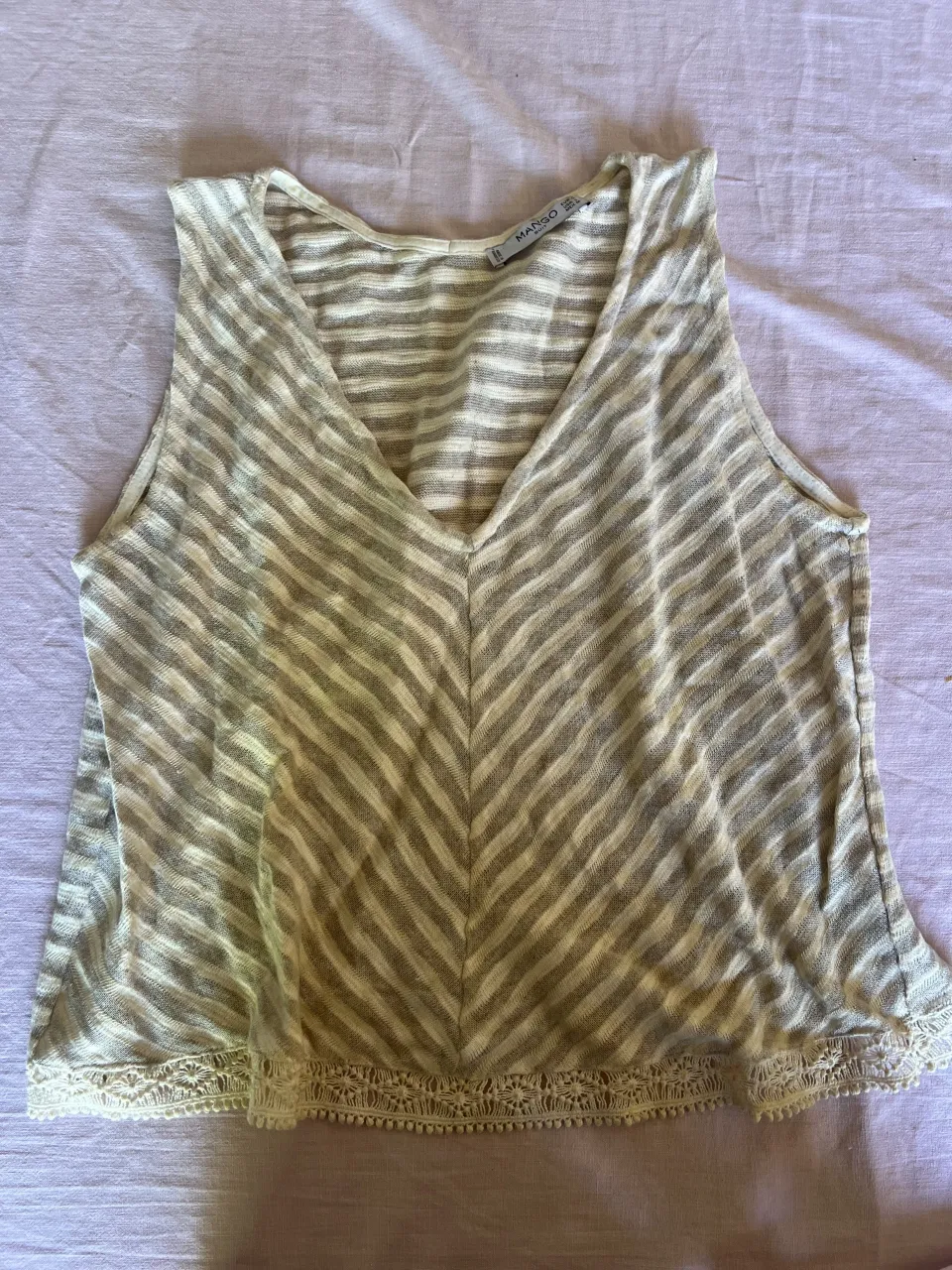 Musculosa de tejido a rayas finas en tonos crudo y gris. Posee detalles de encaje en el borde inferior.