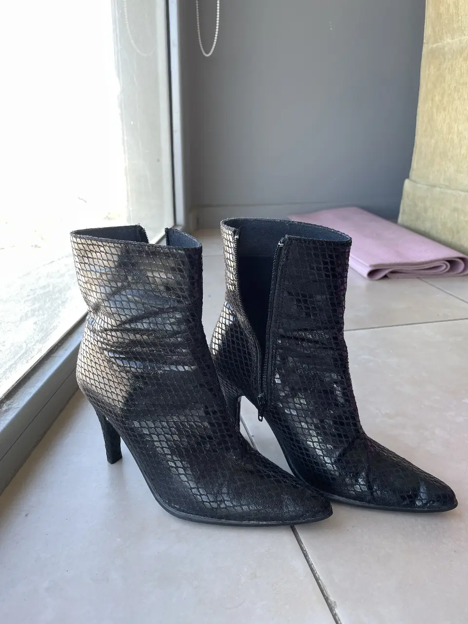 Botines negros de cuero con diseño de reptil. Tienen taco fino y cierre lateral. Ideales para un look elegante y sofisticado.