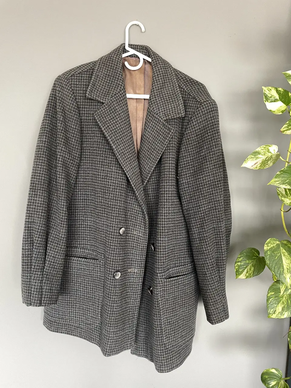 Blazer de hombre vintage con diseño de espiga en tonos grises y marrones. Corte clásico con solapas, dos bolsillos frontales y cierre de dos botones. Interior forrado en tela satinada color marrón claro. Ideal para un look elegante y atemporal.