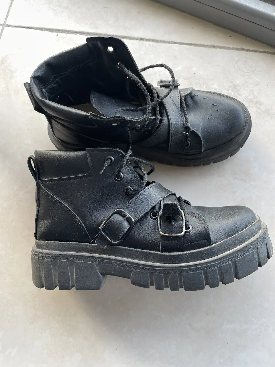 Borcegos negros con hebillas y suela gruesa. tiene pequeño detalle (arañado de gato) en la bota izquierda.