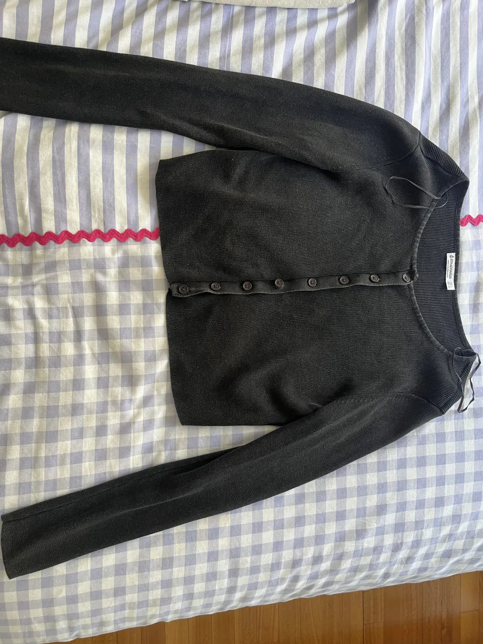 Cardigan crop de manga larga, color gris oscuro. Tiene botones al frente y un escote redondo. Ideal para un look casual y moderno.