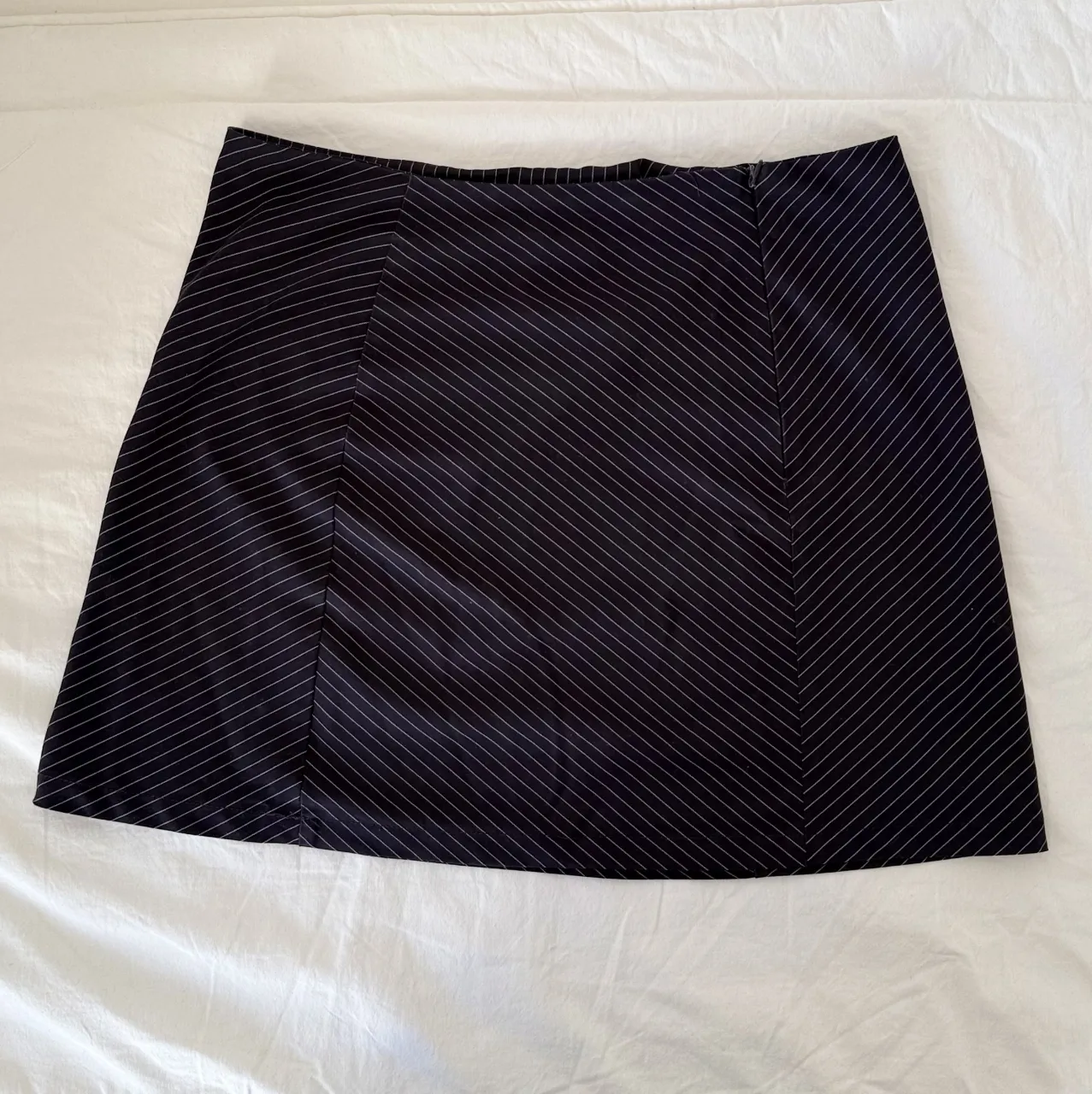 Pollera corta azul con finas rayas blancas. Diseño moderno y versátil, ideal para armar looks cancheros.