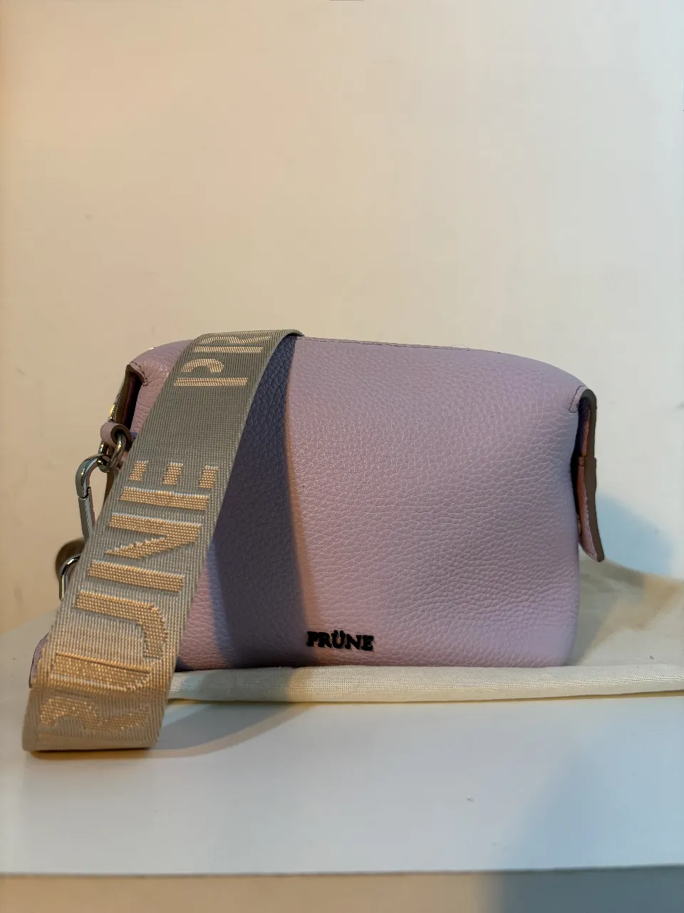 Cartera bandolera PRUNE de cuero lila, ideal para llevar lo esencial con estilo. Perfecta para un look casual o para complementar un outfit de salida.