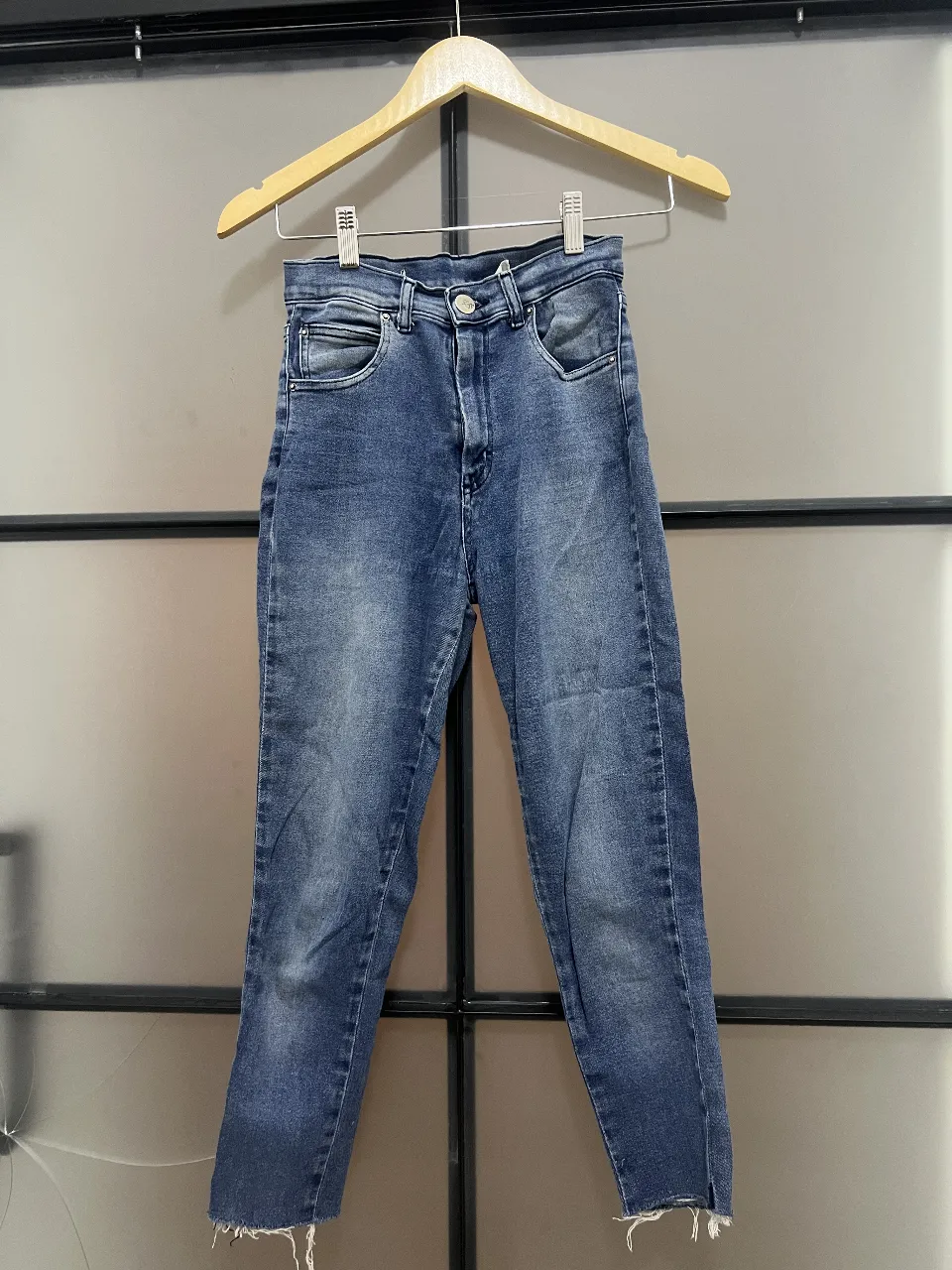 Jeans de mujer tiro alto, con un lavado azul gastado. El corte es recto y el largo es por los tobillos, con un detalle de flecos en el bajo. Marca Complot.