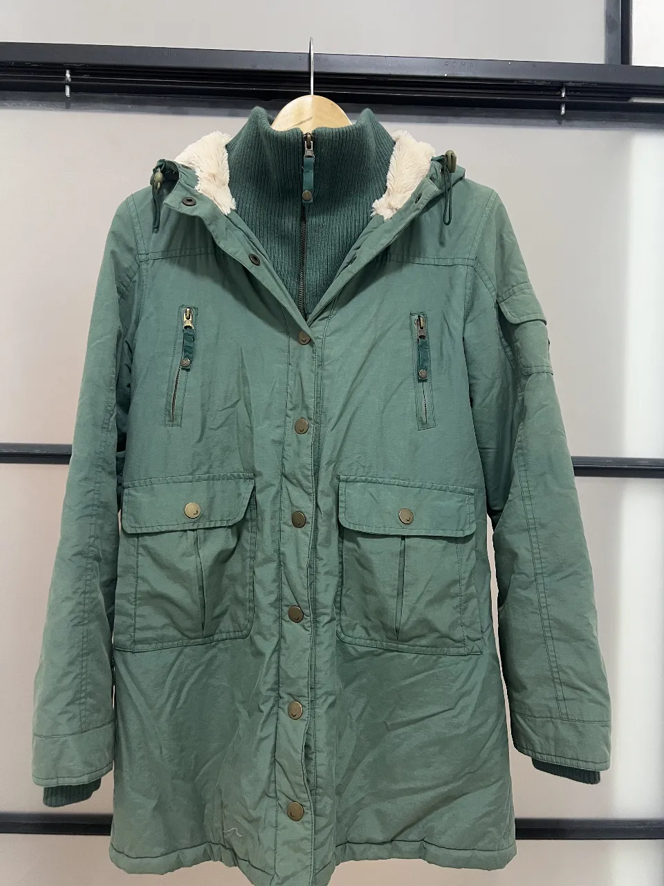 Campera larga verde con capucha y forro de abrigo. Ideal para el invierno, con bolsillos y cierre.