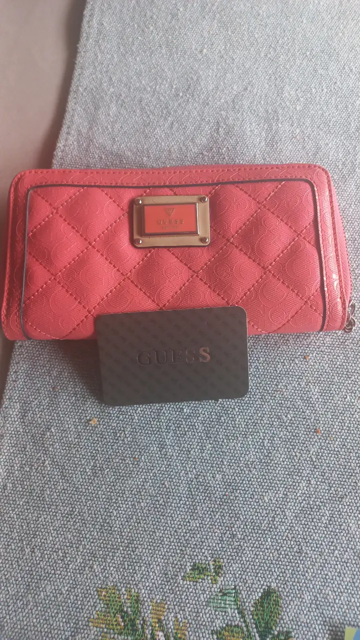 Billetera Guess rosa, con diseño acolchado y detalle metálico con el logo de la marca. Incluye tarjetero Guess.