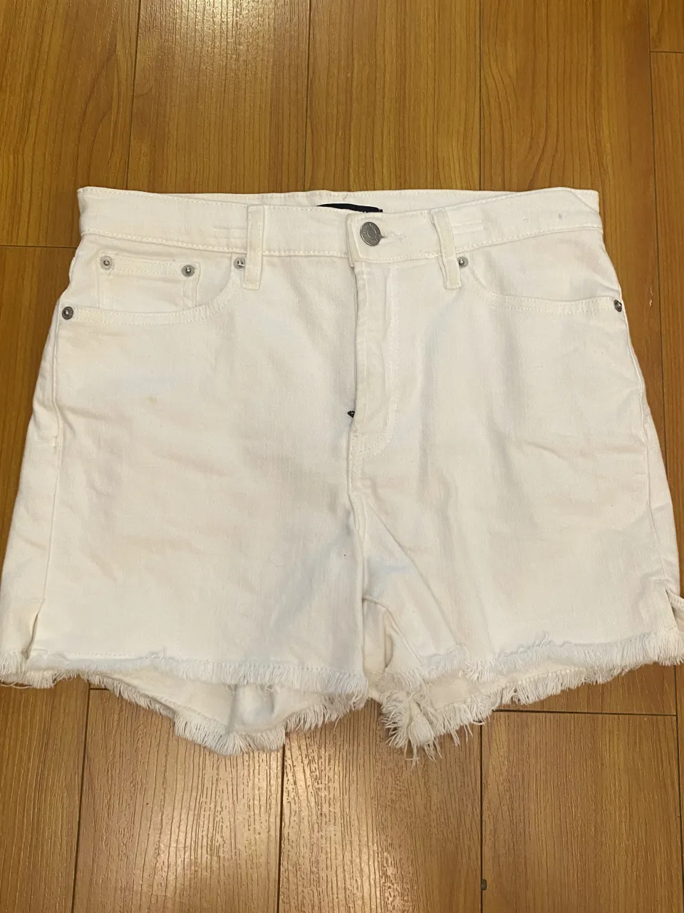 Shorts de jean blancos tiro alto con roturas y detalles desflecados en el ruedo. Un clásico infaltable para los días de sol, súper versátil y canchero.