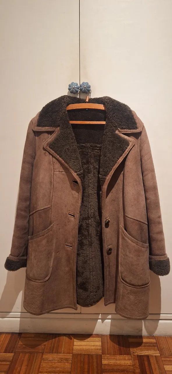 Campera de gamuza marrón con forro de corderito. Tiene cuello solapa, dos bolsillos frontales y cierre de botones.