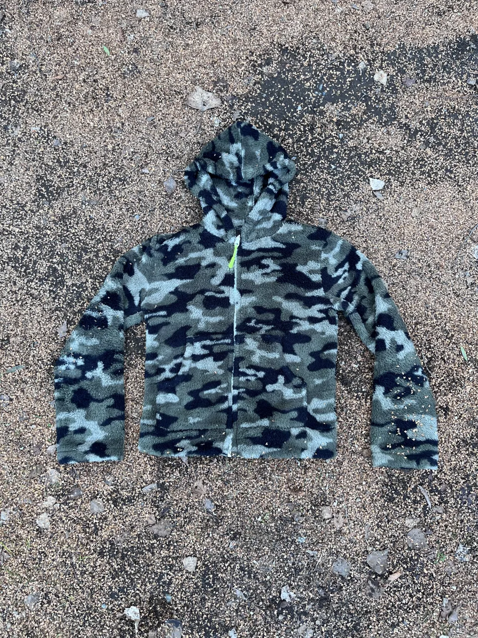 Buzo con capucha y cierre completo, estampado camuflado en tonos verdes y grises. Ideal para un look urbano y relajado. Talle 10