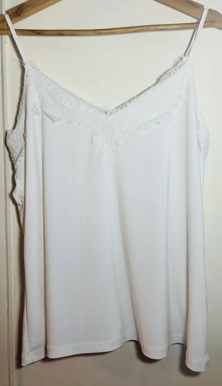 Musculosa blanca con detalles de encaje en el escote. Ideal para un look casual y fresco.