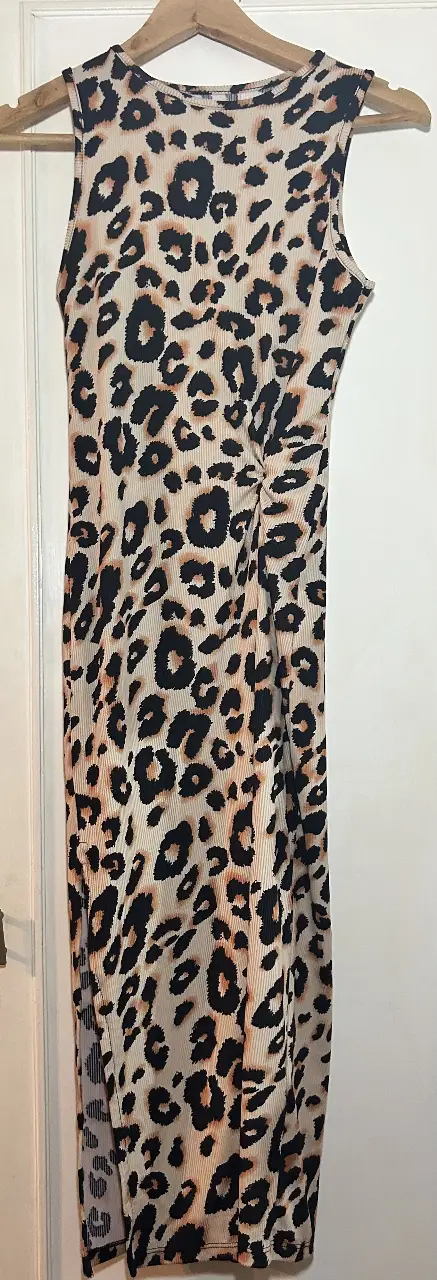 Vestido midi de mujer con estampado de leopardo. Diseño ajustado al cuerpo, sin mangas y con detalle fruncido en un lateral. Ideal para un look moderno y audaz.