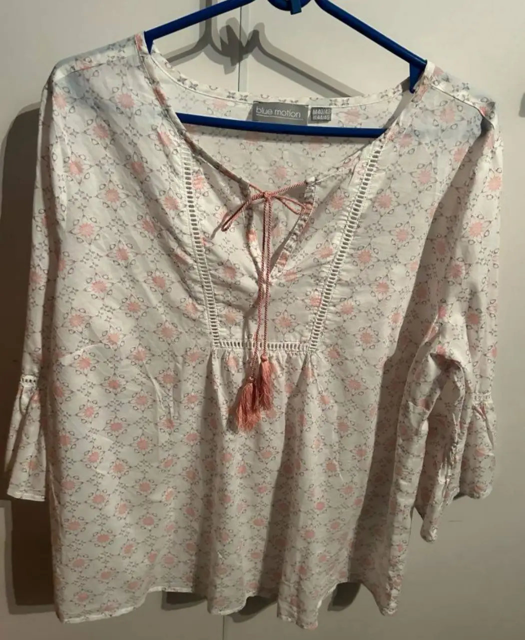 Blusa de mujer con estampado floral en tonos rosa y blanco. Diseño con cuello en V y detalle de lazo, mangas 3/4 con volados. Ideal para un look casual y fresco.