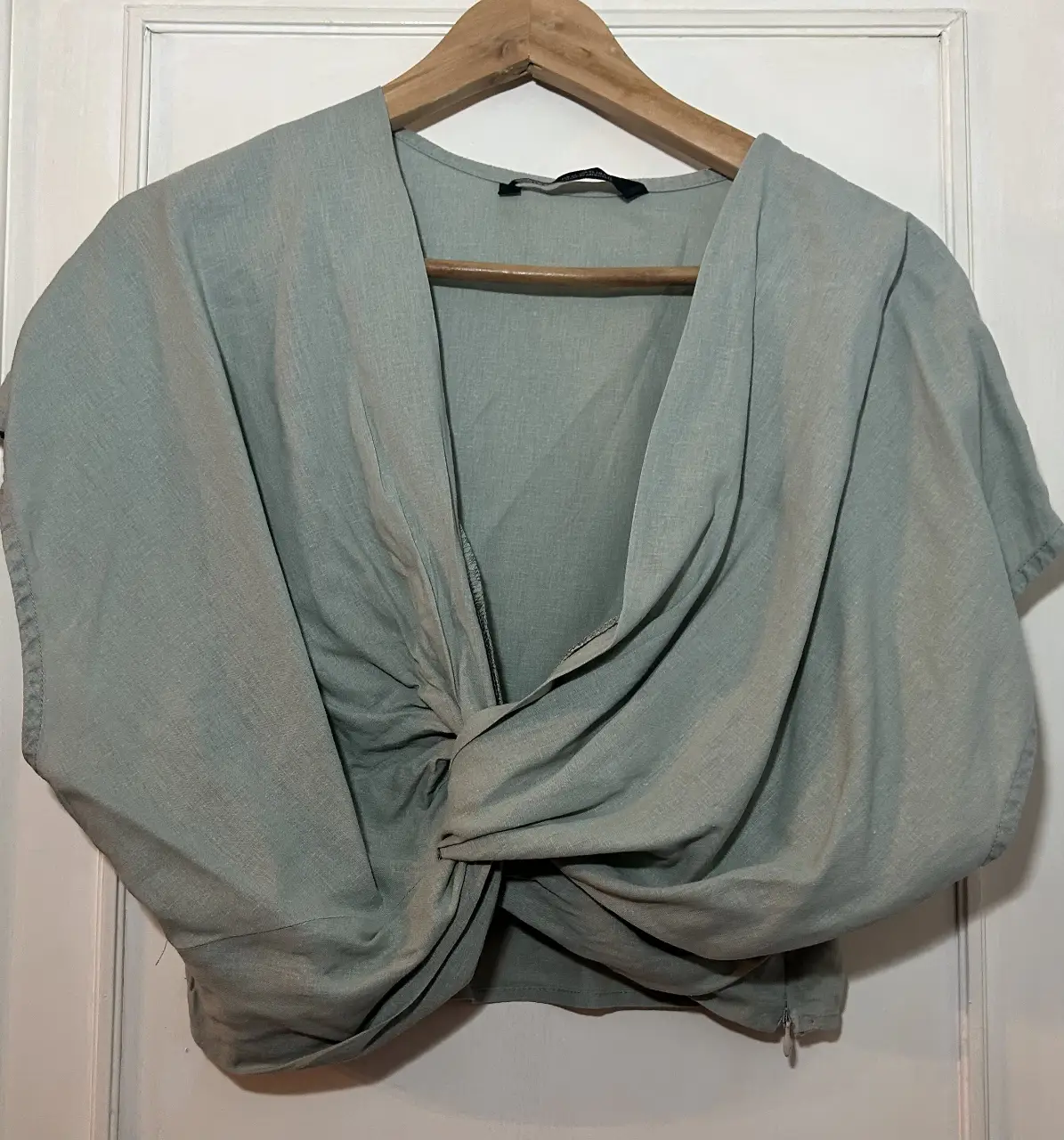 Blusa de mujer en color verde agua, con diseño drapeado y anudado en la parte delantera. Ideal para un look elegante y moderno.