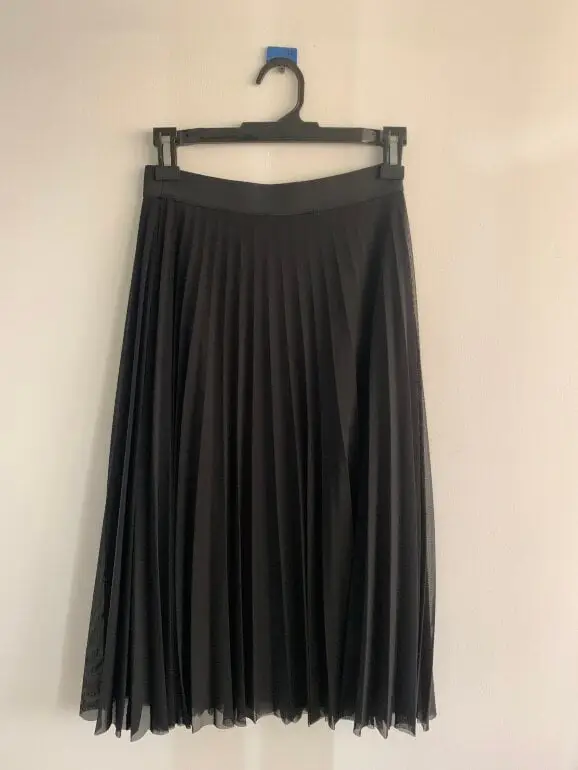 Pollera midi plisada de color negro. Ideal para un look elegante y versátil.