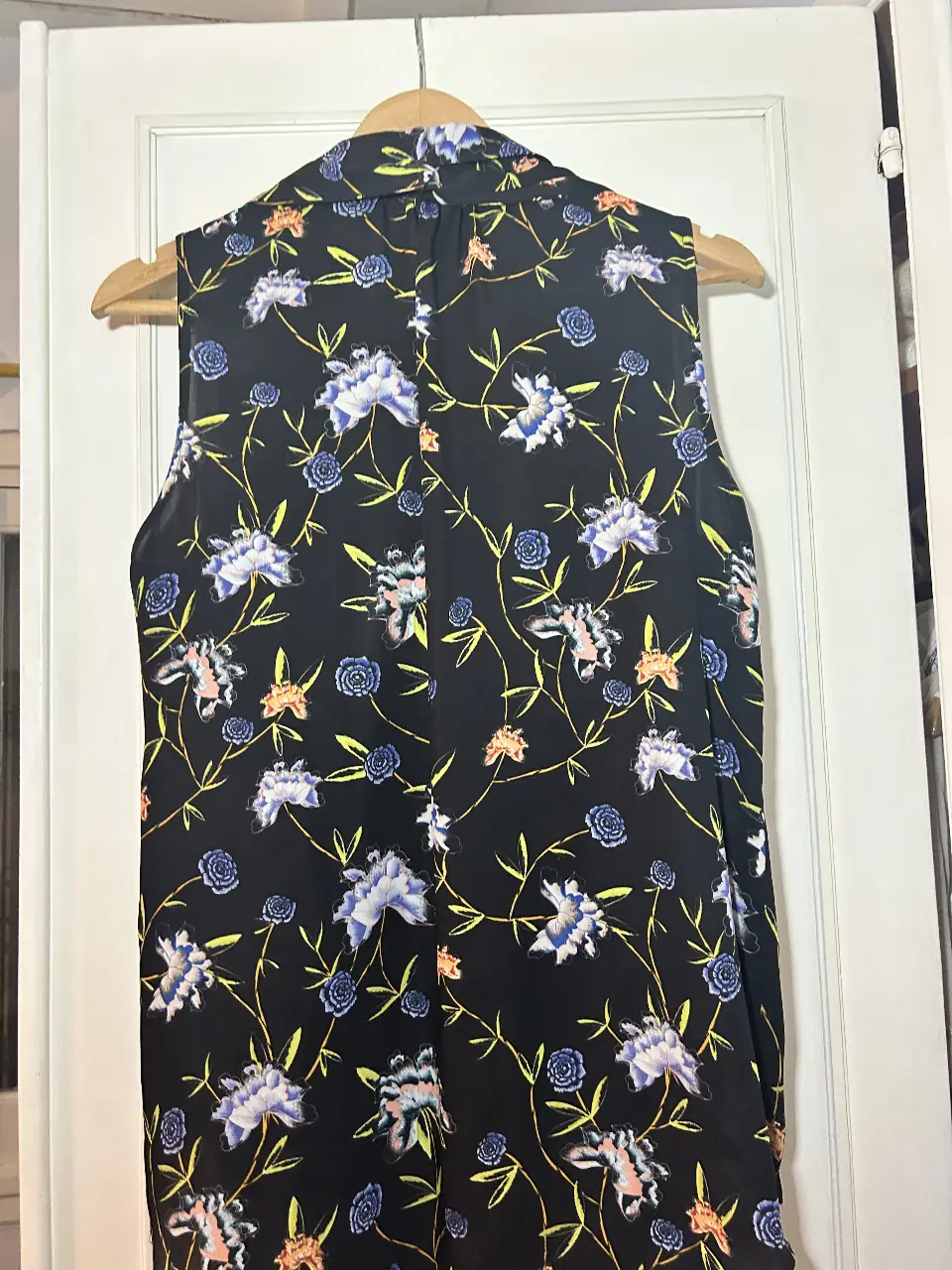 Blusa sin mangas con estampado floral en tonos blanco y azul sobre fondo negro. Ideal para un look fresco y elegante.
