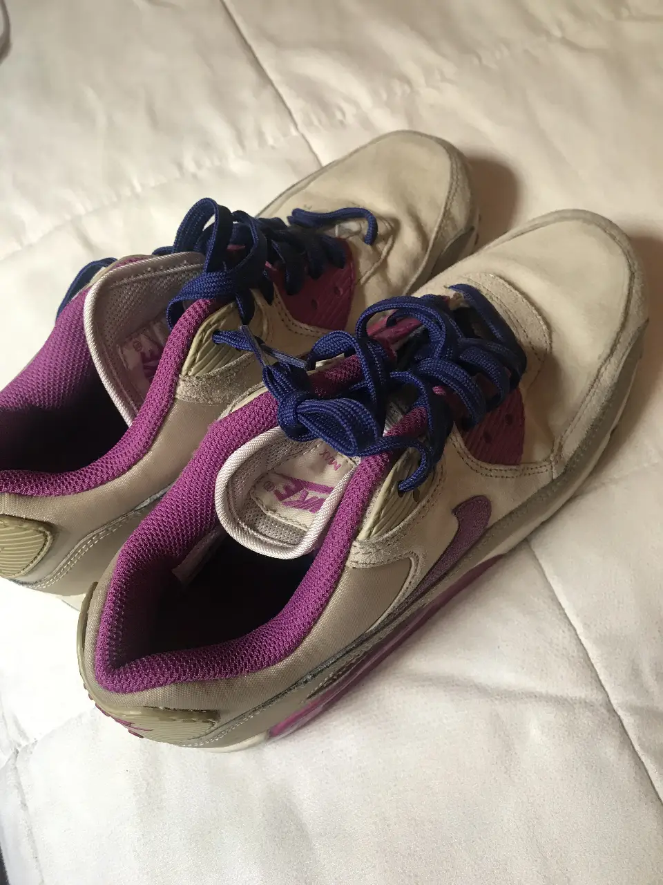 Zapatillas Nike Air Max 90 en tonos crudos con detalles en violeta y azul marino. Ideales para un look casual y urbano.