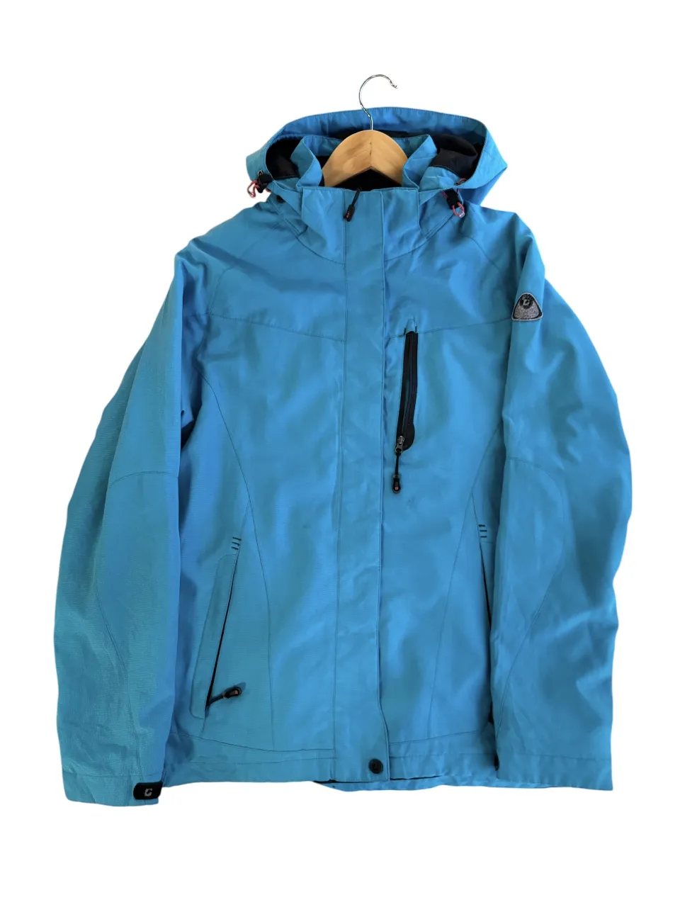 Campera deportiva azul con capucha, ideal para actividades al aire libre. Cuenta con cierre frontal, bolsillos y un diseño funcional para proteger del viento y la lluvia.
Detalle en el cierre del bolsillo derecho 
