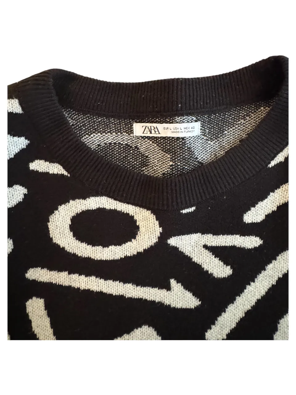 Sweater de hombre de punto grueso, con diseño abstracto en blanco y negro. Cuello en V y puños tejidos. Ideal para un look casual y moderno.