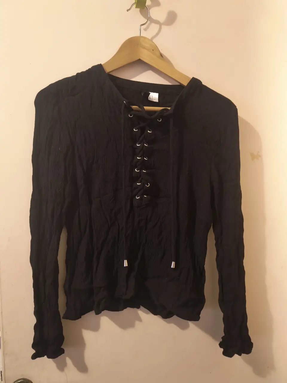 Blusa negra de manga larga con detalle de cordones en el frente. Ideal para un look casual y versátil.