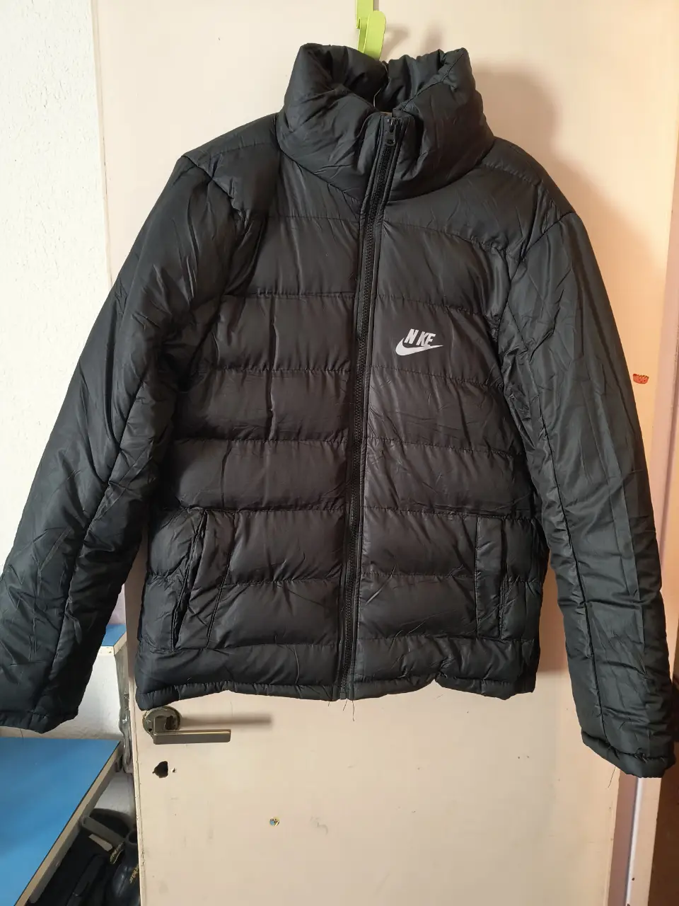 Campera de pluma Nike negra, ideal para el invierno. Con logo de la marca en el pecho y cierre frontal. Perfecta para un look casual y abrigado.