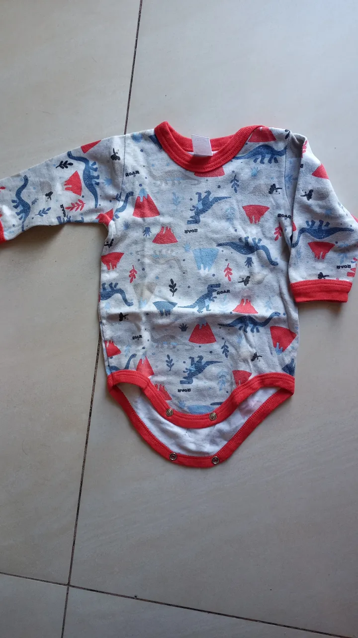 Body de bebé con estampado de dinosaurios, mangas largas y cuello redondo con detalles en rojo. Ideal para mantener a tu bebé cómodo y abrigado.