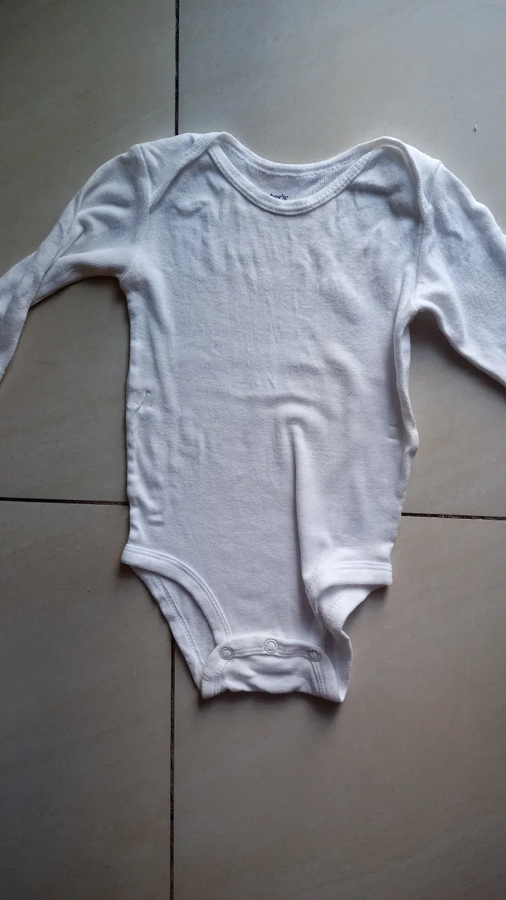 Body blanco de manga larga para bebé, ideal para usar como base en cualquier conjunto. Confeccionado en algodón suave y cómodo.