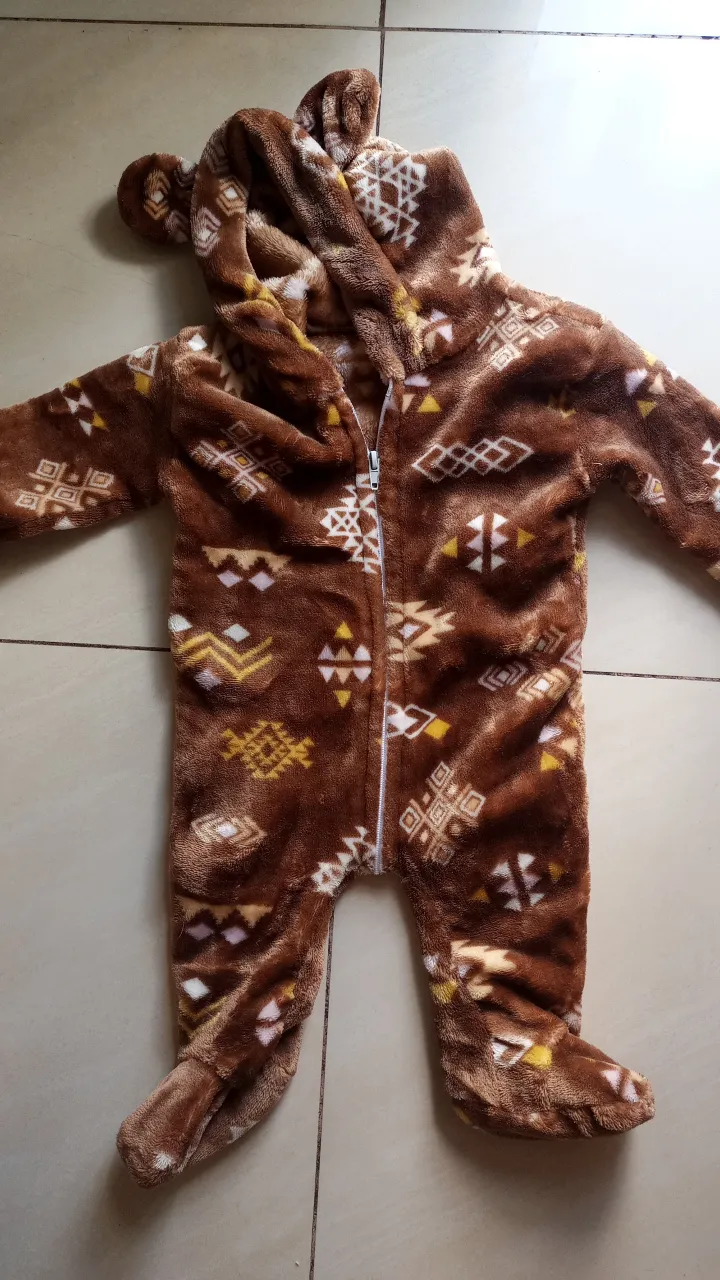 Enterito de bebé con capucha de oso, ideal para el invierno. Confeccionado en tela suave y abrigada, con cierre frontal para facilitar el cambio. Diseño con estampado de motivos geométricos.