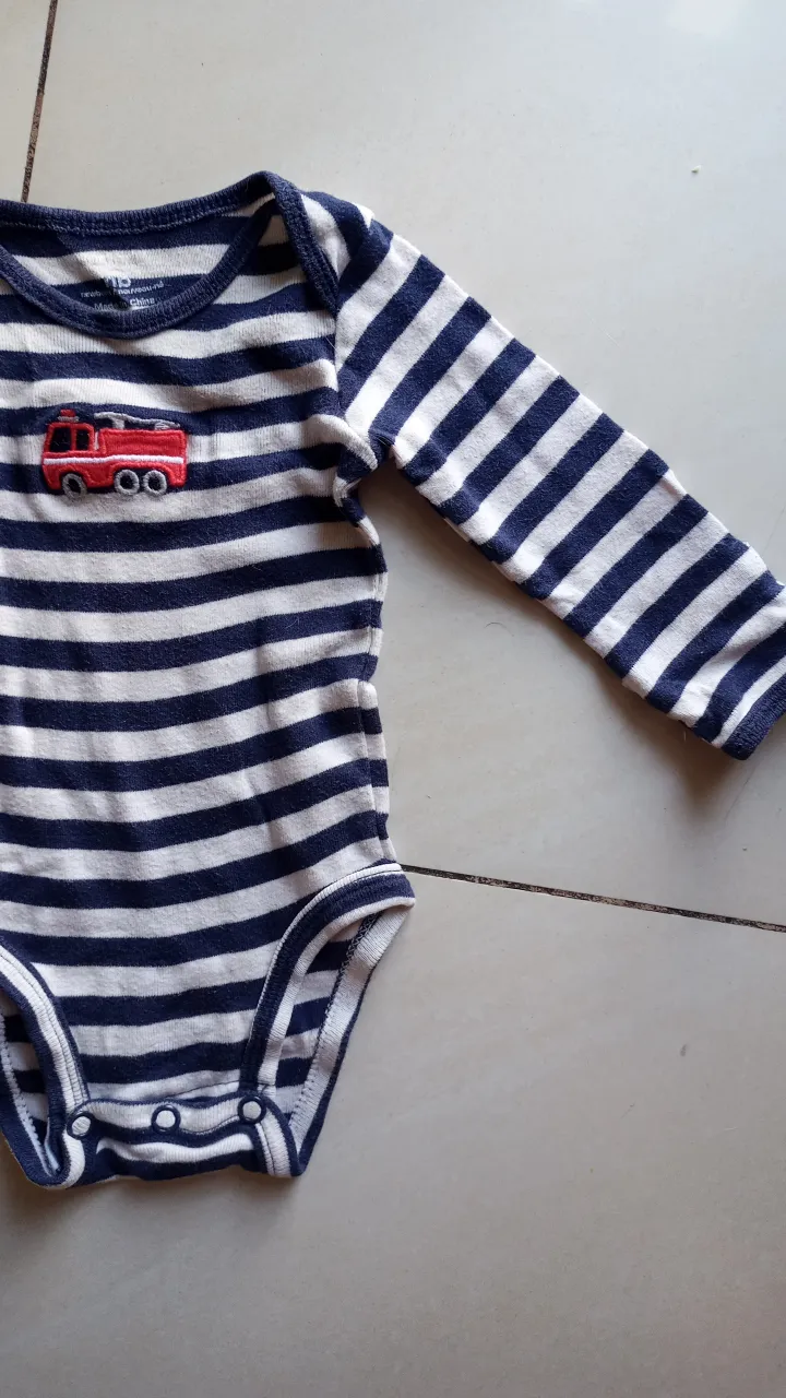 Body de bebé a rayas azul y blanco con un bordado de un camión de bomberos rojo. Ideal para mantener a tu bebé cómodo y a la moda.