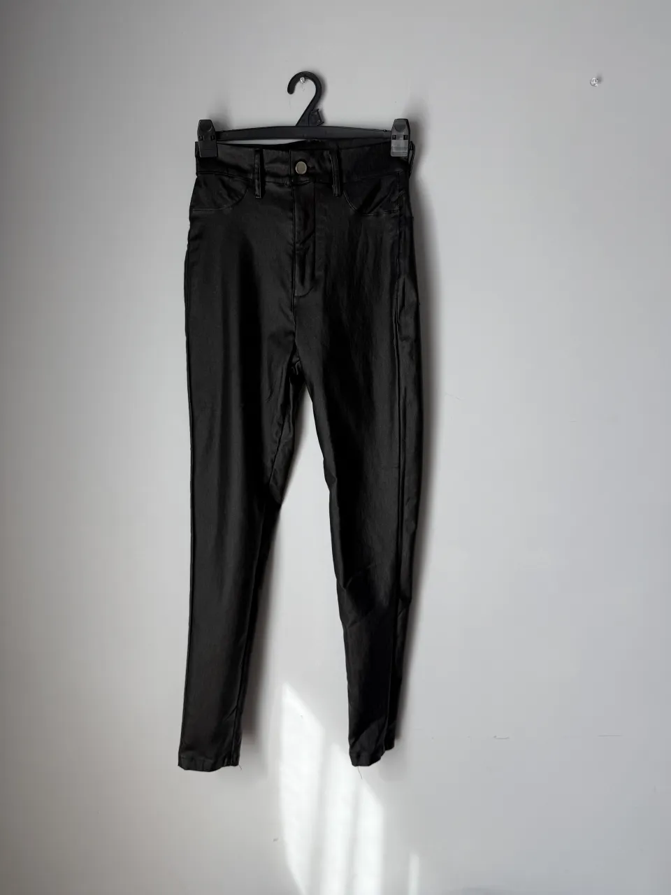 Pantalón negro de cuero sintetico con bolsillos.
