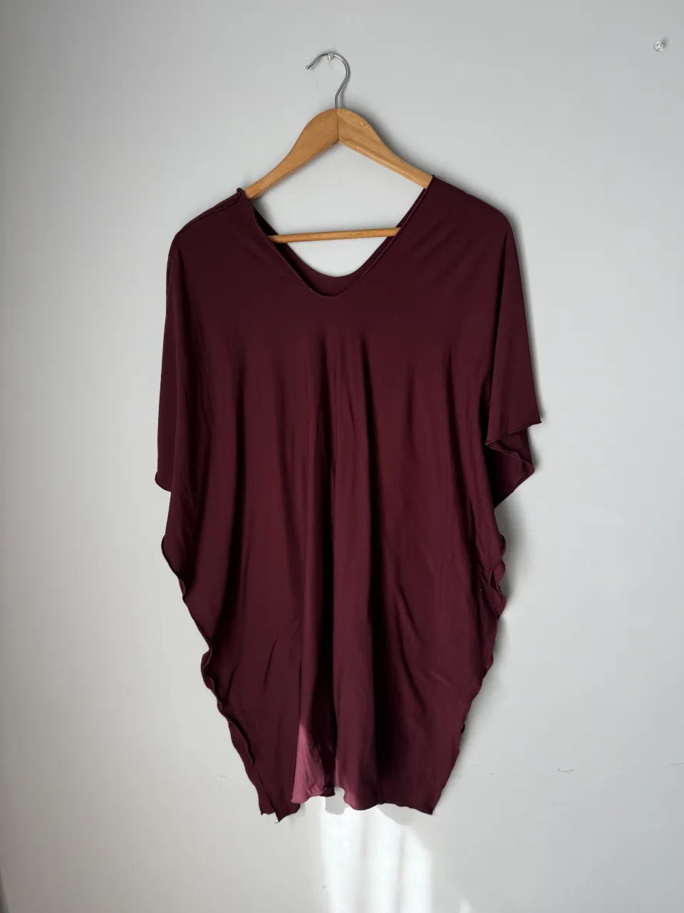 Capa/poncho de color bordo con escote en V y mangas cortas amplias.