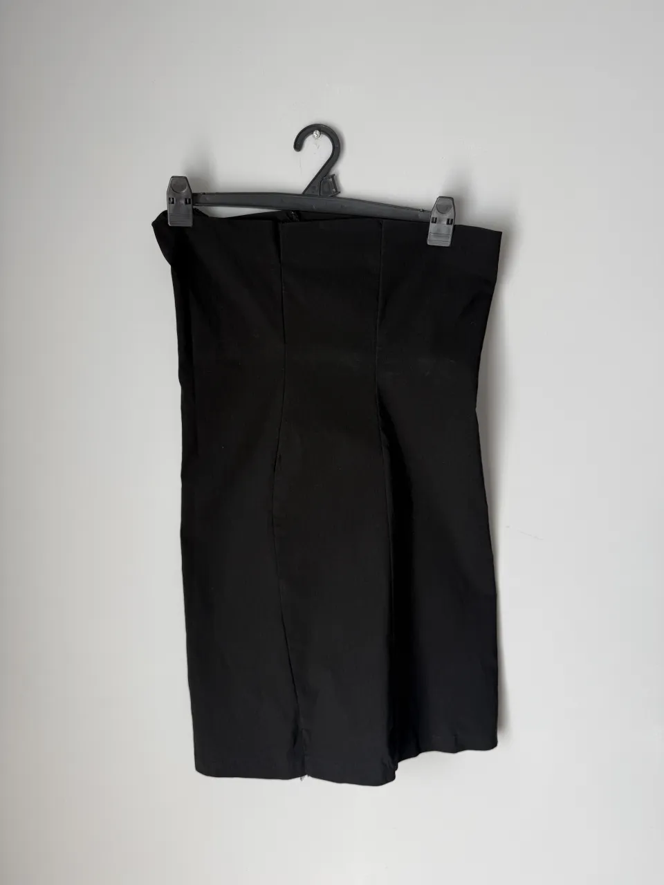 Vestido negro strapless con costuras marcadas en el frente y la espalda.