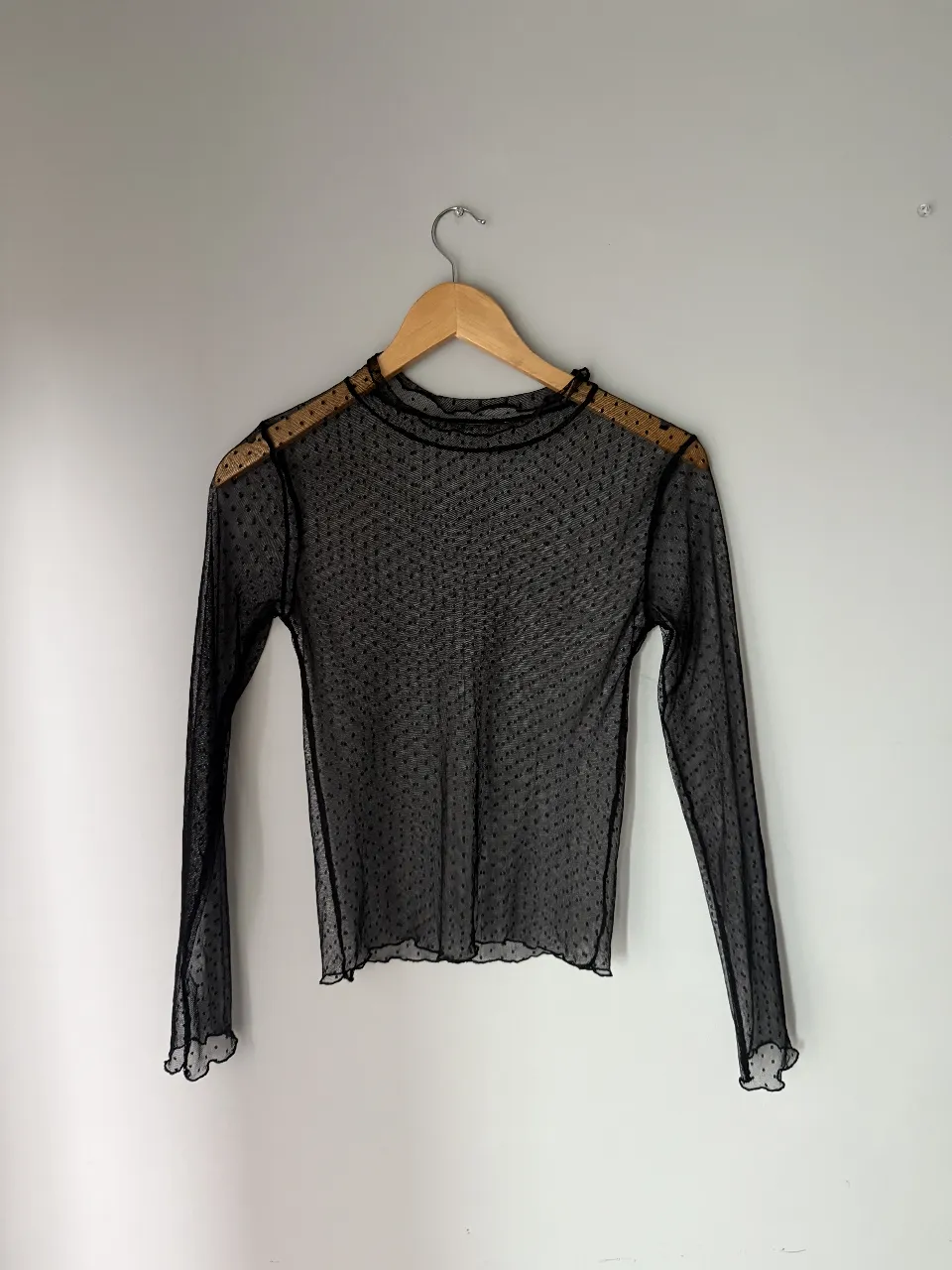 Remera negra de manga larga con cuello alto y estampa de lunares. 