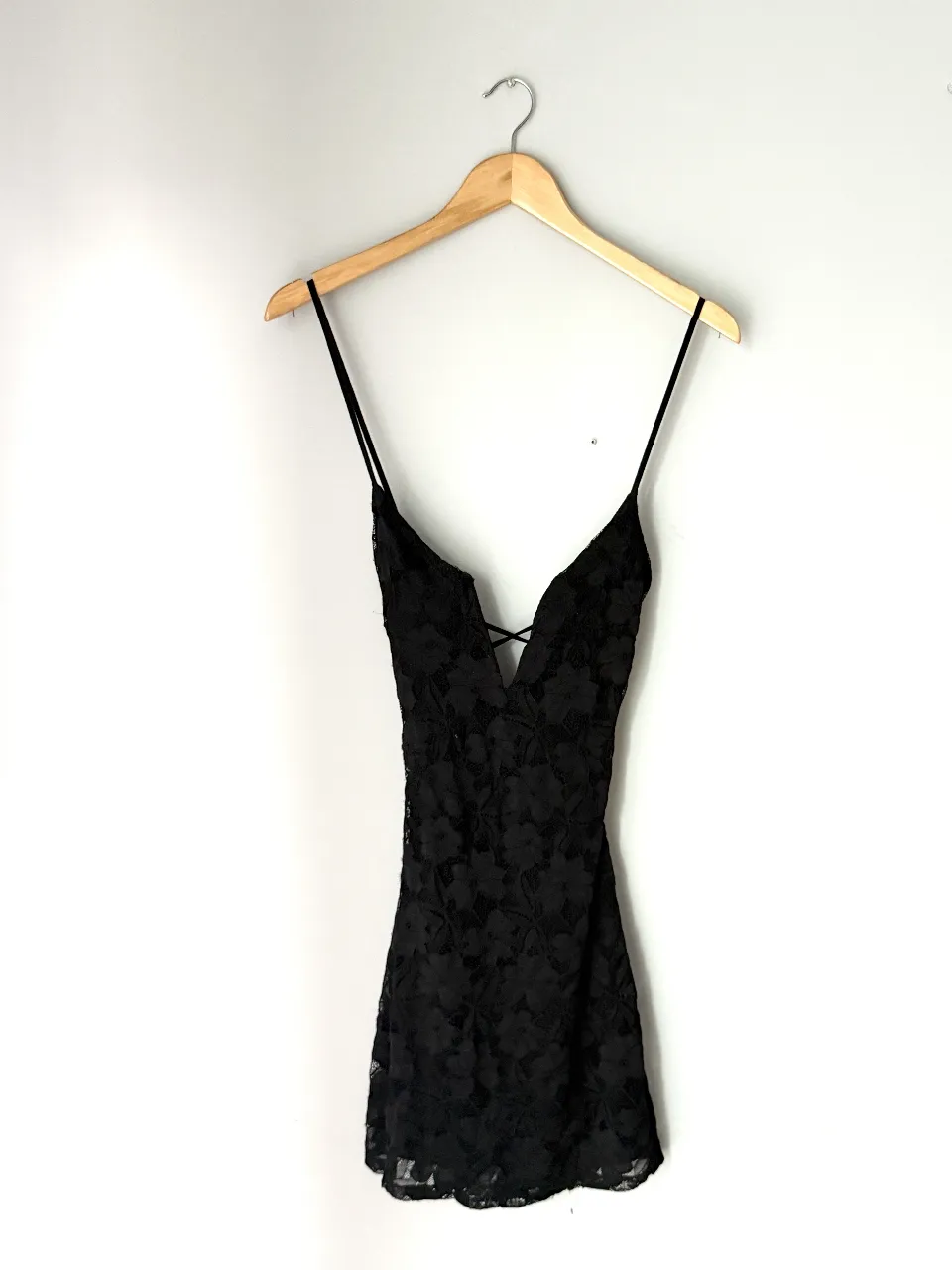 Vestido negro corto con detalles de encaje floral y tiras cruzadas en la espalda. 