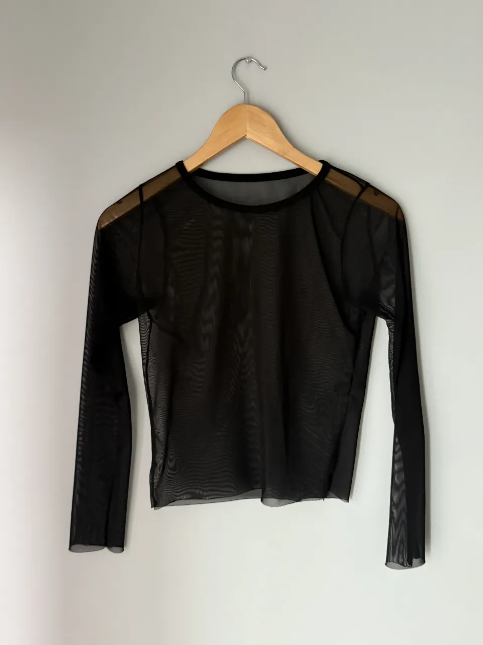 Top negro de manga larga, con un diseño transparente y moderno. 