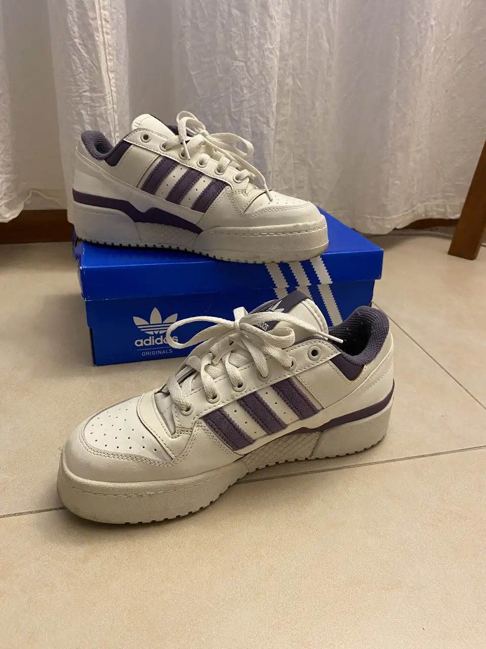 Zapatillas Adidas Forum Bold blancas con detalles en violeta. Tienen el logo de Adidas en la lengüeta y en el lateral. Son ideales para un look casual y urbano.