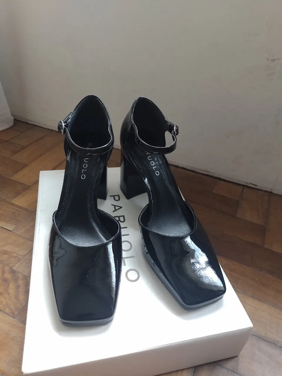 Elegantes tacos negros de charol con pulsera y taco ancho. Ideales para una salida o evento formal.